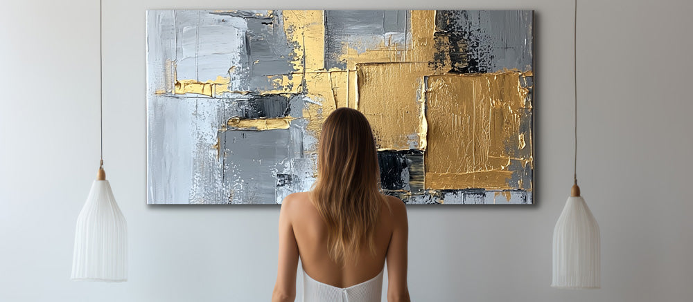 Woman admiring gold and grey canvas artwork with textured lacquer finish
