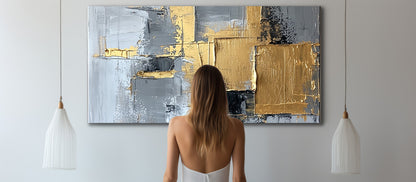 Woman admiring gold and grey canvas artwork with textured lacquer finish